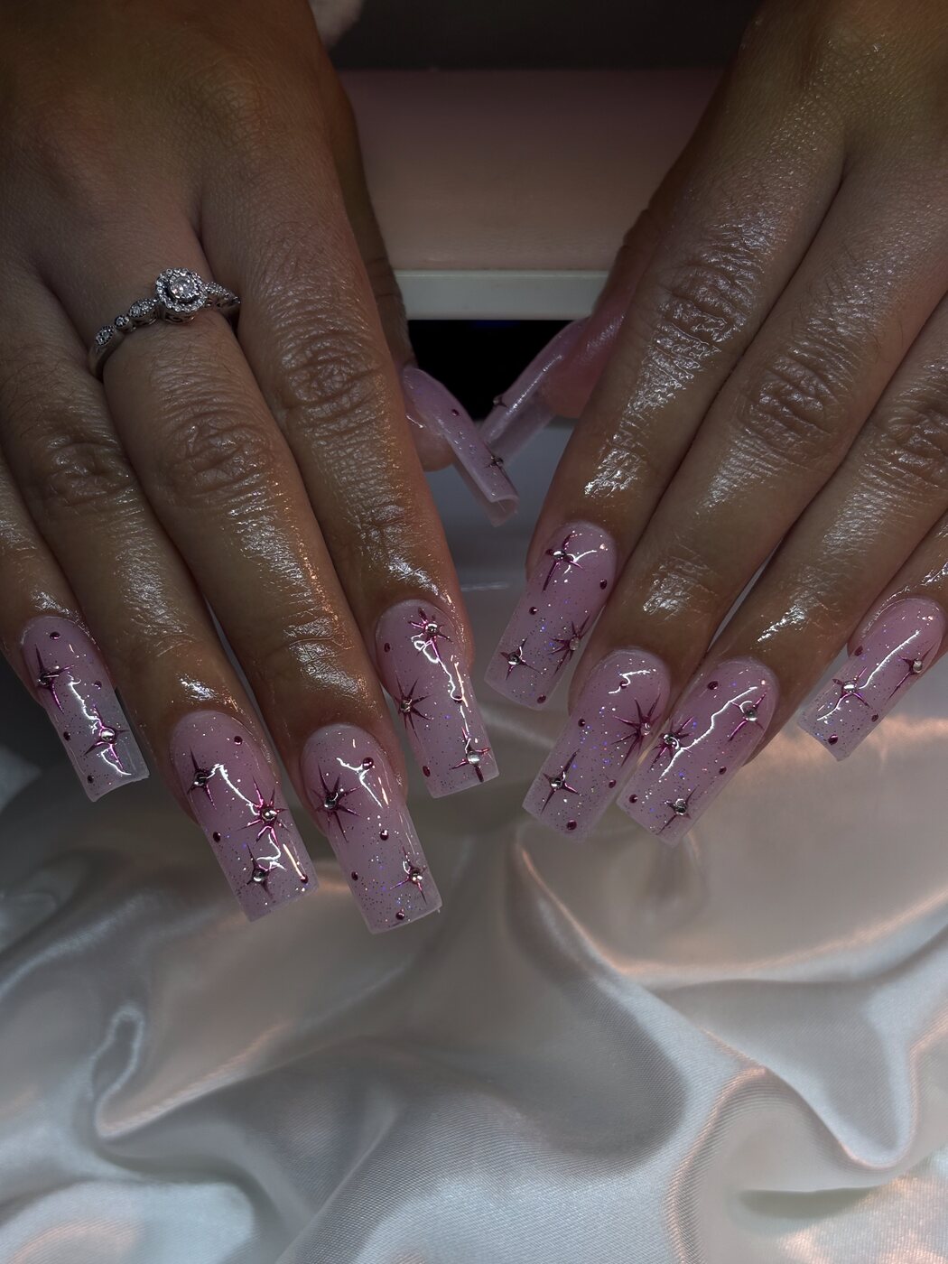 Pink shimmer coffin-shape acrylic set with silver and burgundy celestial star nail art and rhinestones